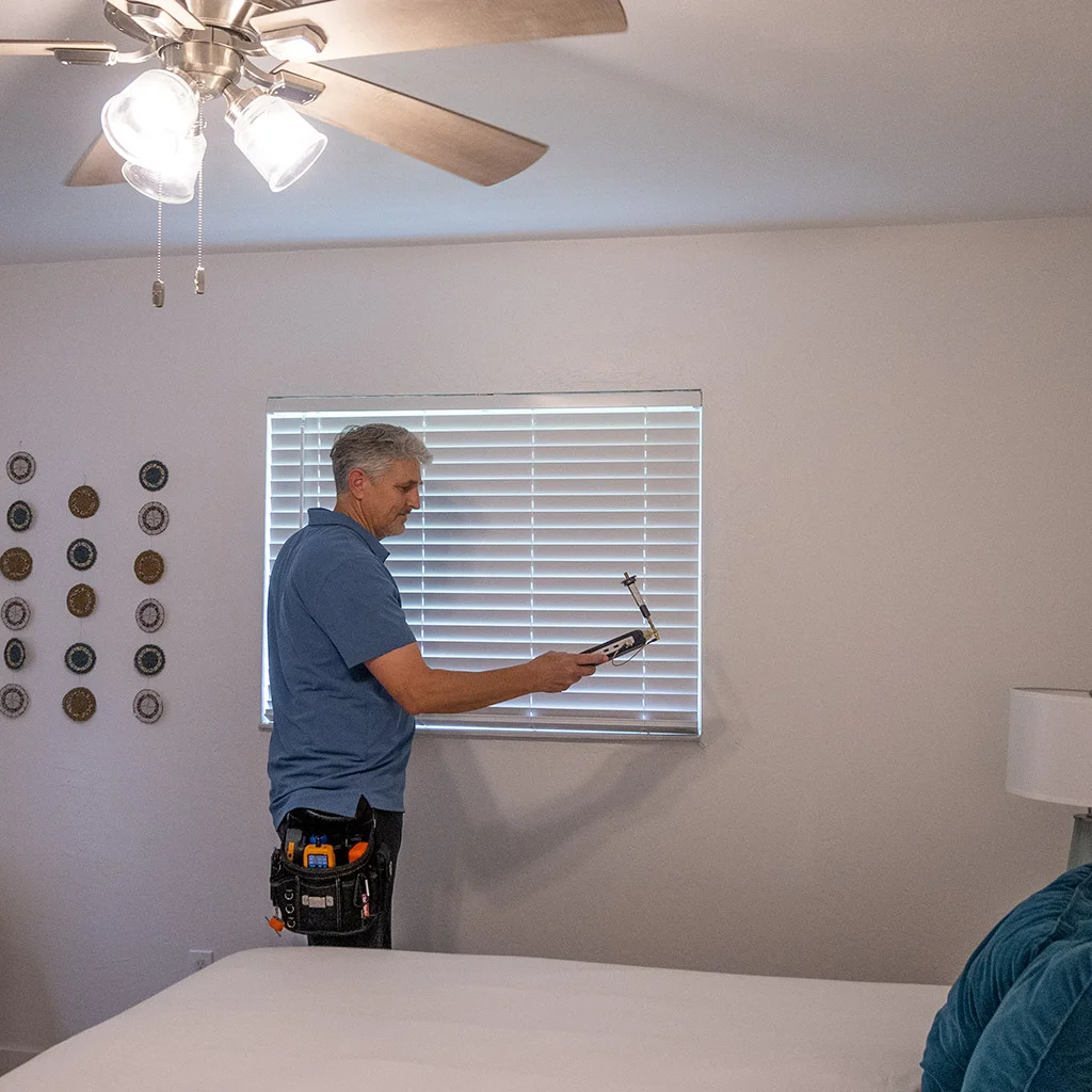 Kit Brucker measuring a bedroom with a meter near the window